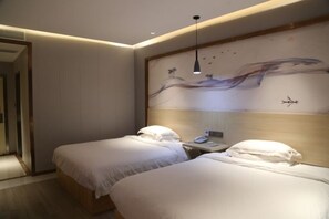 Une chambre d’hôtel avec deux lits, une table de chevet, un tableau au mur et un luminaire suspendu.