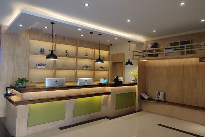 A reception area with a wooden reception desk, multiple pendant lights, and shelves with decorative items.