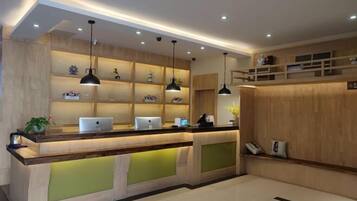 A reception area with a wooden reception desk, multiple pendant lights, and shelves with decorative items.