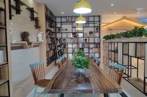 Un comedor con una larga mesa de madera, sillas y lámparas colgantes amarillas.