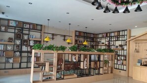 Un intérieur moderne avec des étagères en bois, des suspensions lumineuses jaunes et une plante d’ornement placée au centre.
