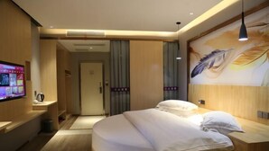 Une chambre d’hôtel moderne avec un lit aux lignes courbes, un téléviseur à écran plat et une grande fresque murale.