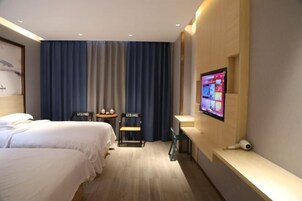 Habitación de hotel con dos camas, televisión, escritorio y una silla.