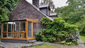Une maison en pierre dotée d’une véranda en verre et d’un chemin en pierre menant à l’entrée.