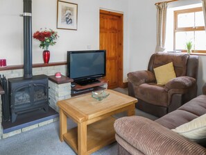A cozy living room with a fireplace, a television, a comfortable sofa, and a wooden coffee table.