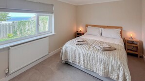 A bedroom with a bed, two bedside tables, a window with a view, and a radiator. - 2 bedroom accommodation in Port Isaac (Port Isaac)