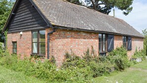 A small brick building with a sloped roof, surrounded by greenery and a large tree. - 2 bedroom accommodation in Wadhurst, near Tunbridge Wells (Wadhurst, near Tunbridge Wells)
