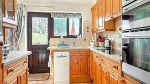 A compact kitchen with wooden cabinets, a built-in oven, and a dishwasher. - 3 bedroom accommodation in Ringstead, near Hunstanton (Ringstead, near Hunstanton)