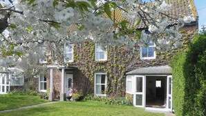 Une maison à deux étages, construite en briques, avec un jardin à l’avant.