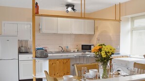 Una cucina moderna con mobili bianchi, un tavolo da pranzo in legno e un vaso di fiori.