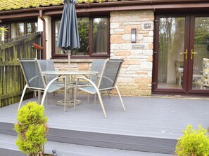 A patio with a table and chairs, a stone wall, and a door with a number plate. - 2 bedroom accommodation in Lelant, near St Ives (Lelant, near St Ives)