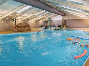 An indoor swimming pool with clear water, a rock formation, and a water slide. - 2 bedroom accommodation in Lelant, near St Ives (Lelant, near St Ives)
