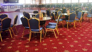 A banquet hall with round tables and chairs, a stage, and large windows. - 2 bedroom accommodation in Lelant, near St Ives (Lelant, near St Ives)