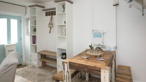 Una habitació acollidora amb una taula de menjador de fusta, una biblioteca blanca i una petita banca.