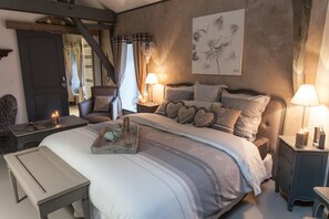 Un dormitorio con cama, mesitas de noche, un banco y una obra de arte colgada en la pared.
