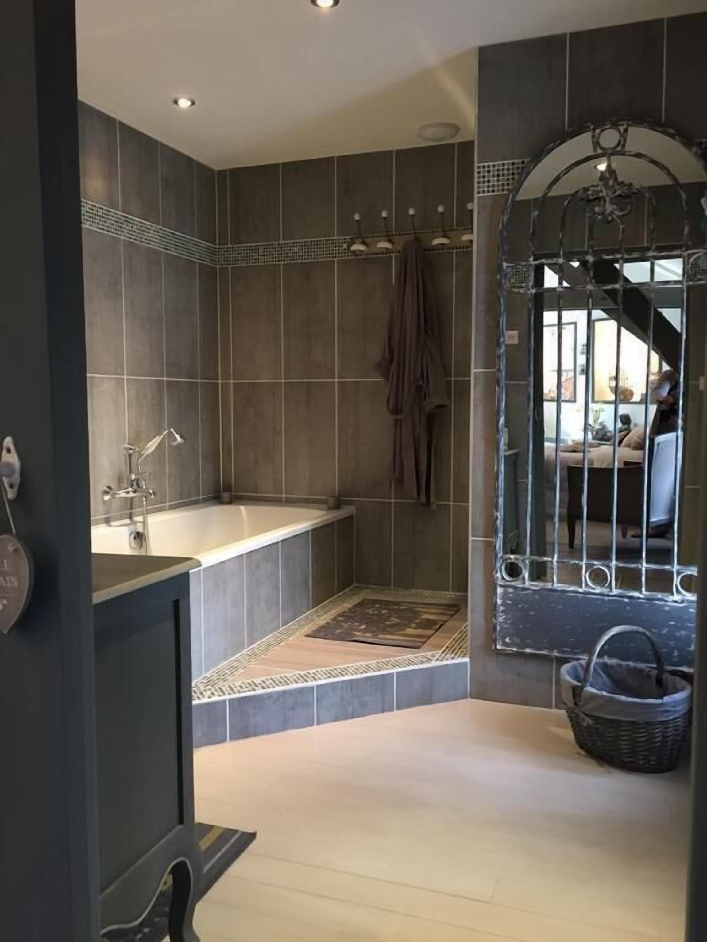 Un bagno moderno con una vasca da bagno ampia, una zona doccia e una finestra decorativa con inferriate.