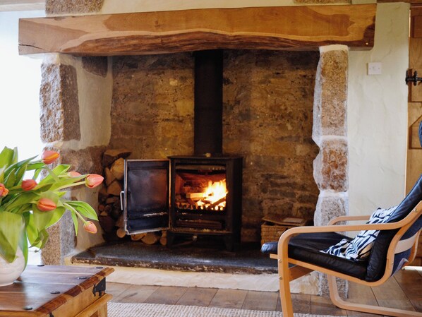 A cozy room with a stone fireplace, a comfortable chair, and a vase of tulips.