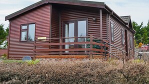 A wooden cabin with a porch and a small staircase leading up to the entrance.