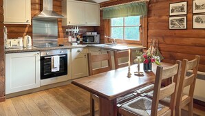 Una cocina acogedora con paredes de madera, una mesa de comedor con sillas, un microondas y un lavaplatos.
