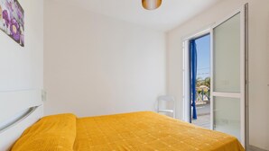 Una habitación con cama, una silla y una puerta que da a un espacio al aire libre.