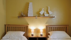 A hotel room with two single beds, wooden headboards, a nightstand with a lamp, and wall decor including a stack of boxes and two white bird figurines. - 2 bedroom accommodation in Brampton, nr Appleby (Brampton, nr Appleby)
