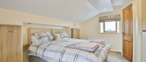 A bedroom with a bed, a wardrobe, a radiator, and a window with a view.