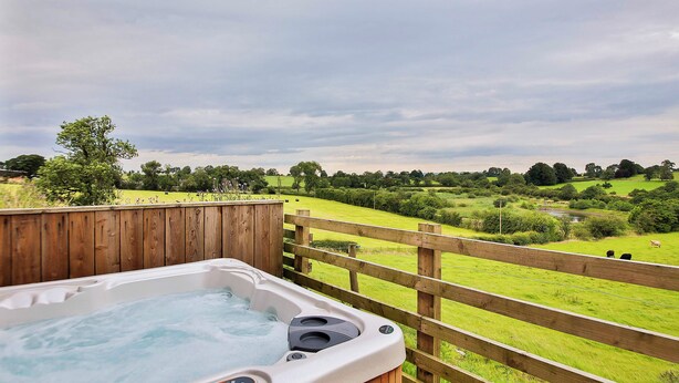 A hot tub on a wooden deck with a view of a green field and trees. - 1 bedroom accommodation in Sawley, near Clitheroe (Sawley, near Clitheroe)