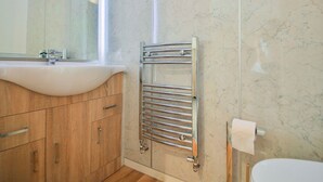 A bathroom with a white sink, wooden cabinets, a chrome towel rack, and a marble wall. - 1 bedroom accommodation in Sawley, near Clitheroe (Sawley, near Clitheroe)