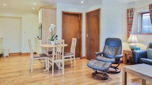 A living room with a wooden dining table, four chairs, a sofa, a rocking chair, and a window with curtains. - 1 bedroom accommodation in Sawley, near Clitheroe (Sawley, near Clitheroe)