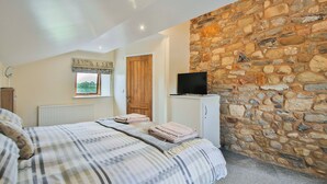 A bedroom with a bed, a television on a cabinet, a stone wall, and a window with a view. - 1 bedroom accommodation in Sawley, near Clitheroe (Sawley, near Clitheroe)