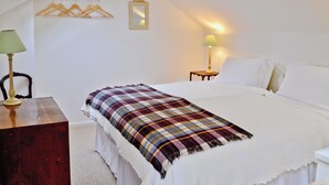 A bedroom with a bed, a bedside table with a lamp, a mirror, and a coat rack. - 1 bedroom accommodation in Laverton, near Ripon (Laverton, near Ripon)