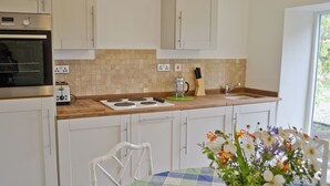 A kitchen with white cabinets, a stove, a toaster, and a sink. There is a window with a view of greenery outside. - 1 bedroom accommodation in Laverton, near Ripon (Laverton, near Ripon)