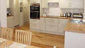 A modern kitchen with white cabinets, wooden countertops, a built-in oven, and a sink. - Bodwen Corner Cottage (Wootton Bridge)