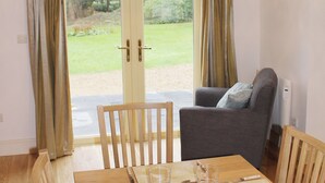 A dining area with a wooden table, chairs, and a grey sofa. - Bodwen Corner Cottage (Wootton Bridge)