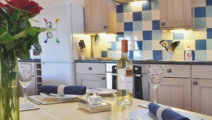 Une cuisine bien éclairée, avec un dosseret à carreaux, une bouteille de vin et une table à manger.