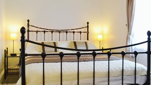Un lit avec un cadre en métal, deux lampes de chevet et un tapis à rayures.