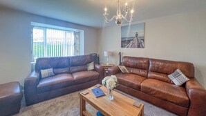 A living room with two brown leather sofas, a wooden coffee table, and a chandelier. - 2 bedroom accommodation in Sutton-on-Sea, near Mablethorpe (Sutton-on-Sea, near Mablethorpe)