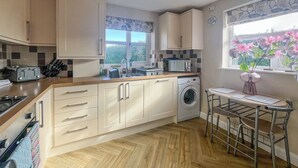 A compact kitchen with a washing machine, a microwave, and a small dining area with a table and chairs. - 2 bedroom accommodation in Sutton-on-Sea, near Mablethorpe (Sutton-on-Sea, near Mablethorpe)