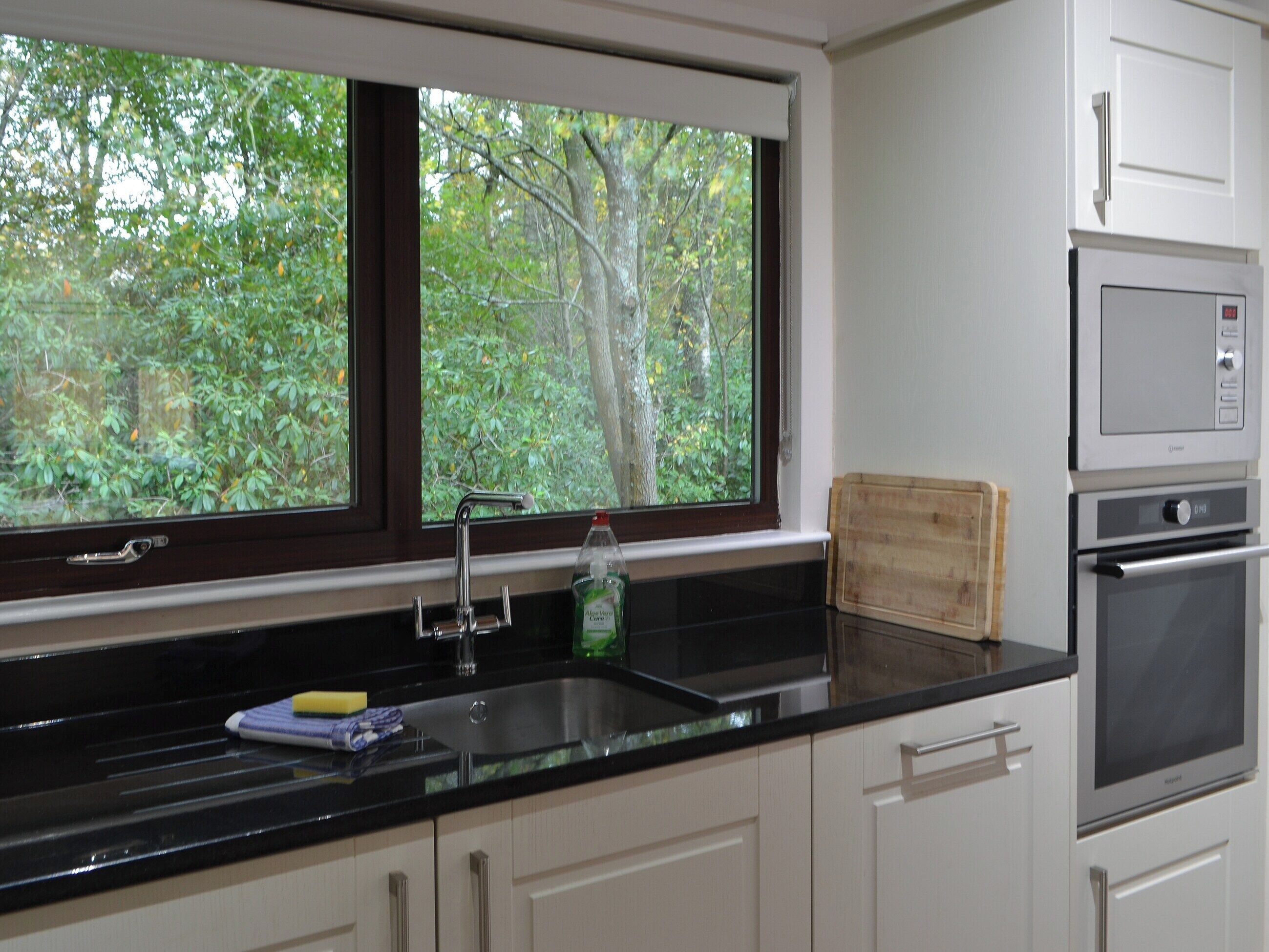 A kitchen with a window, a sink, a cutting board, and an oven.