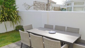 Um pátio externo com uma mesa retangular e seis cadeiras de vime.