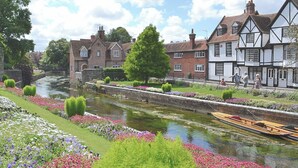 Un canal où naviguent des bateaux, bordé de parterres de fleurs et de bâtiments traditionnels.