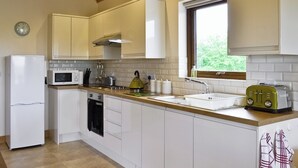 A modern kitchen with white cabinets, a microwave, a kettle, a toaster, and a sink. - 3 bedroom accommodation in Burgh le Marsh, near Skegness (Burgh le Marsh, near Skegness)