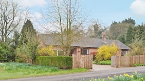 A quaint cottage with a tiled roof, surrounded by a well-maintained garden with daffodils.