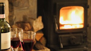 Une bouteille de vin et deux verres de vin rouge sont posés sur une table devant une cheminée.