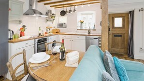 Une cuisine avec des poutres en bois, une table à manger avec des chaises, un four à micro-ondes et un évier.