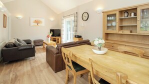 Ein modernes Wohnzimmer mit einem Holzesstisch, Ledersofas und einem Fernseher.