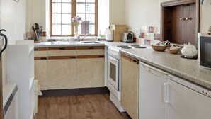 Una cocina moderna con armarios blancos, horno empotrado, lavavajillas y encimera de granito.