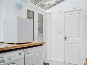A compact laundry room with a washing machine, dryer, and a small window.