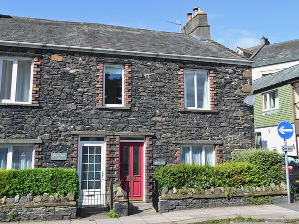A stone building with a red door, multiple windows, and a blue directional sign. - 4 bedroom accommodation in Keswick (Keswick)
