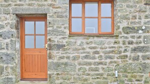 A stone building with a wooden door and a window.